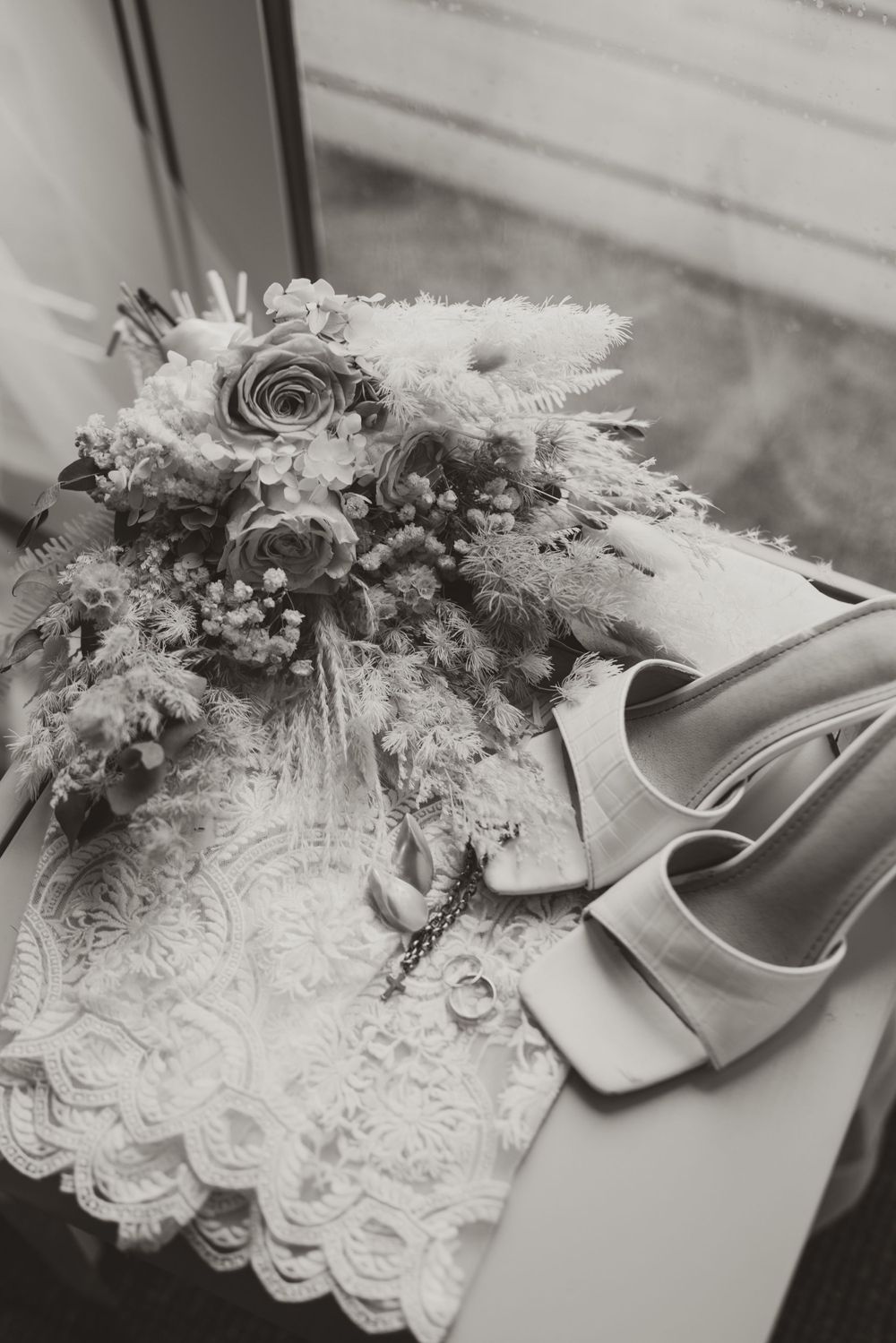 A delicate bridal bouquet with roses and lace details captured in black and white.
