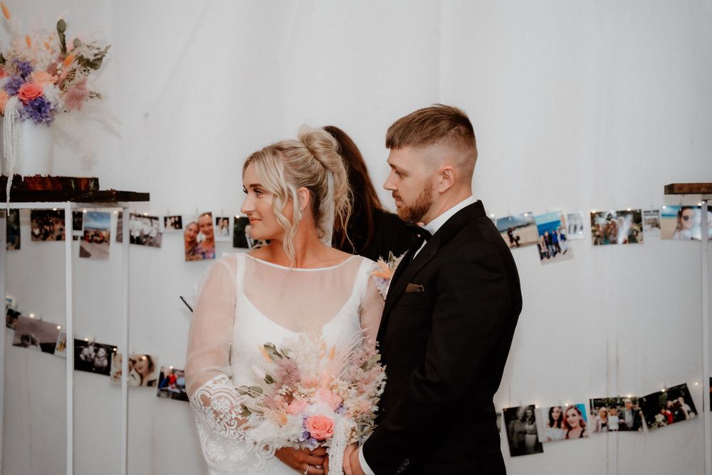 Couple sharing intimate moment under photo display at wedding ceremony.