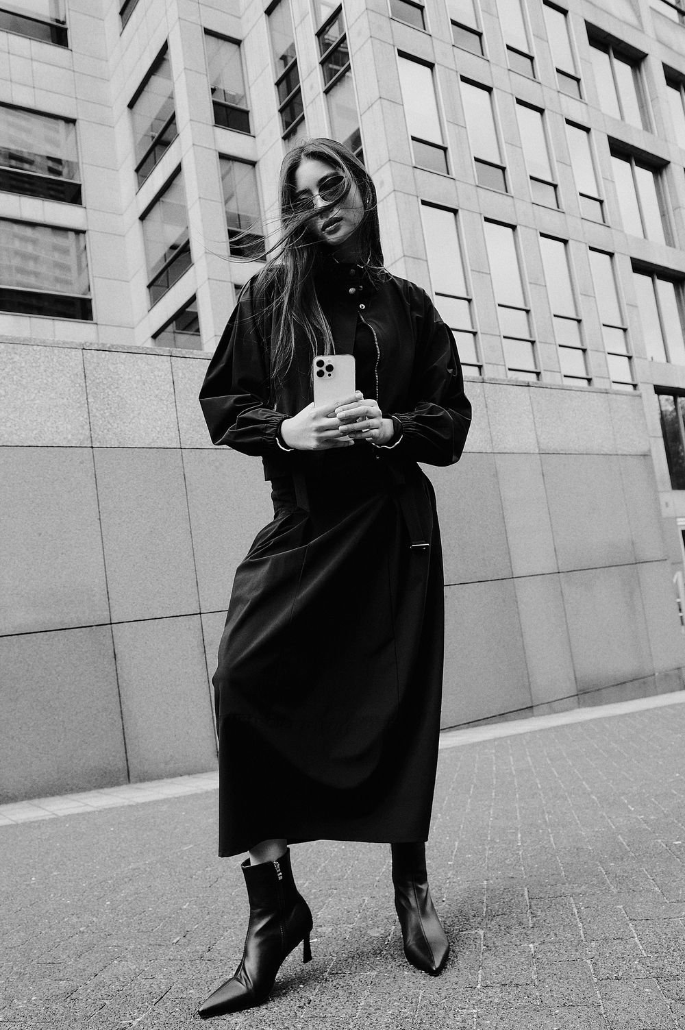 A series of black and white fashion photographs showing someone in a dark coat and boots against an urban building wall.