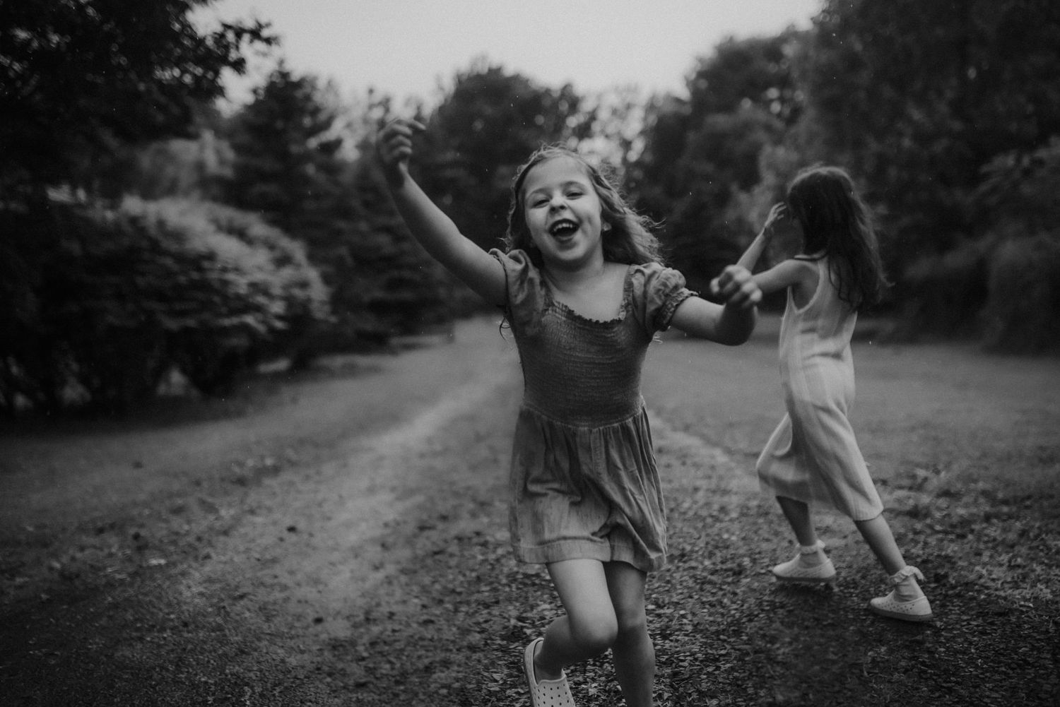 joyful black and white candid photos show playful running and leaping moments captured outdoors in nature.