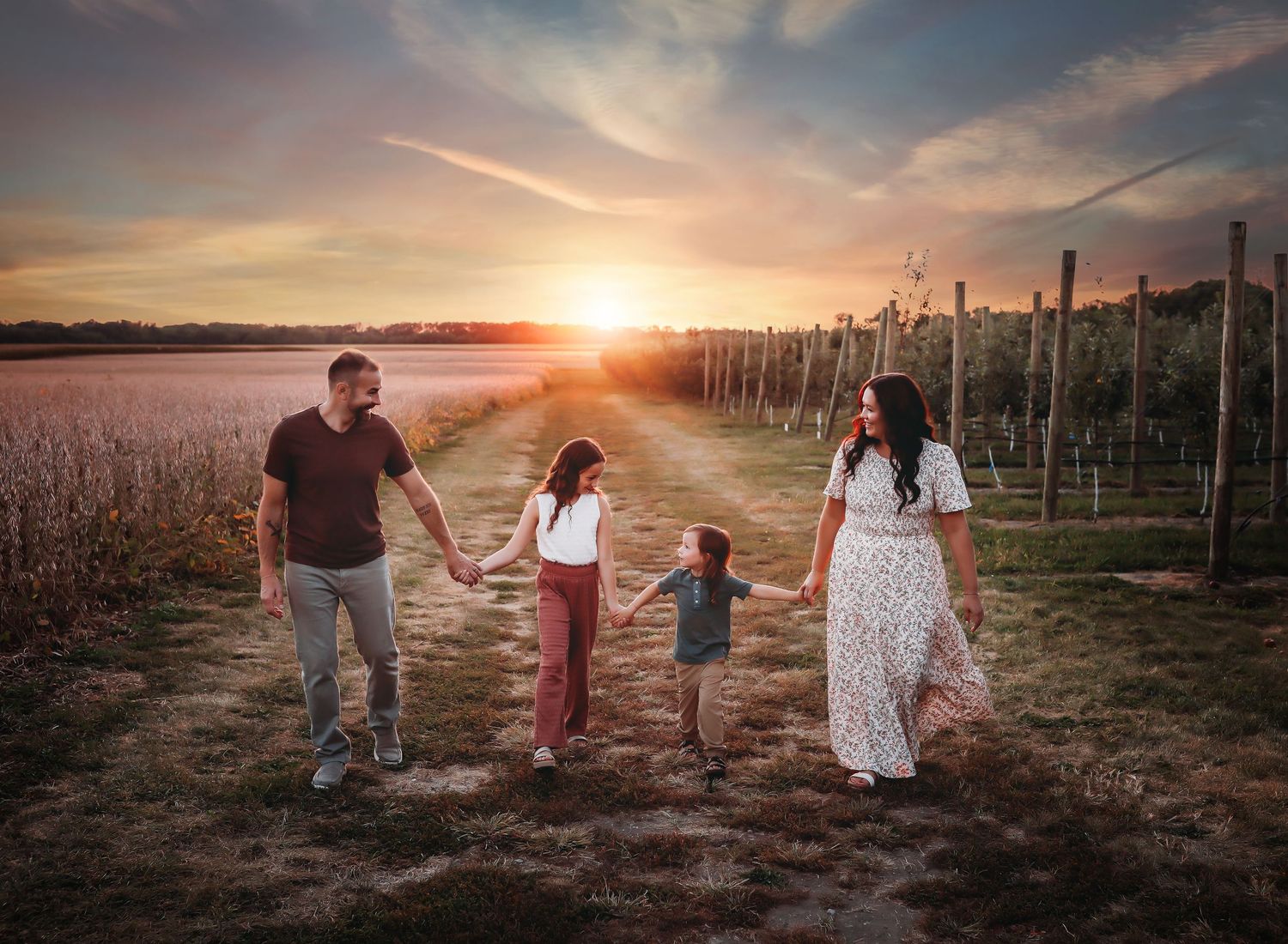 Family silhouettes walking together in vineyard during golden sunset.