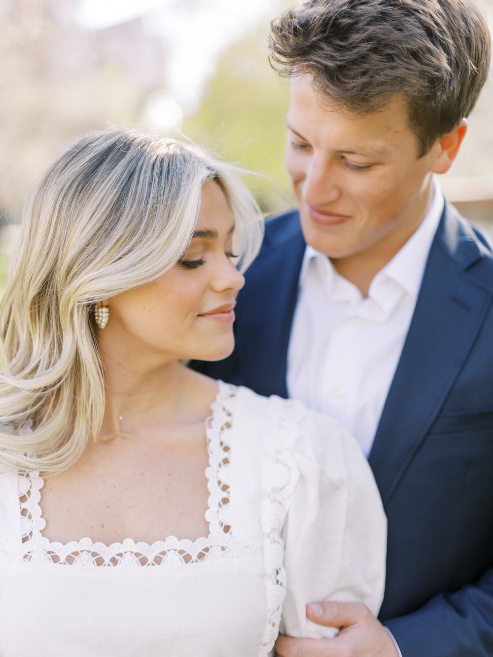 A romantic engagement photo features a couple in navy and white sharing an intimate moment outdoors.