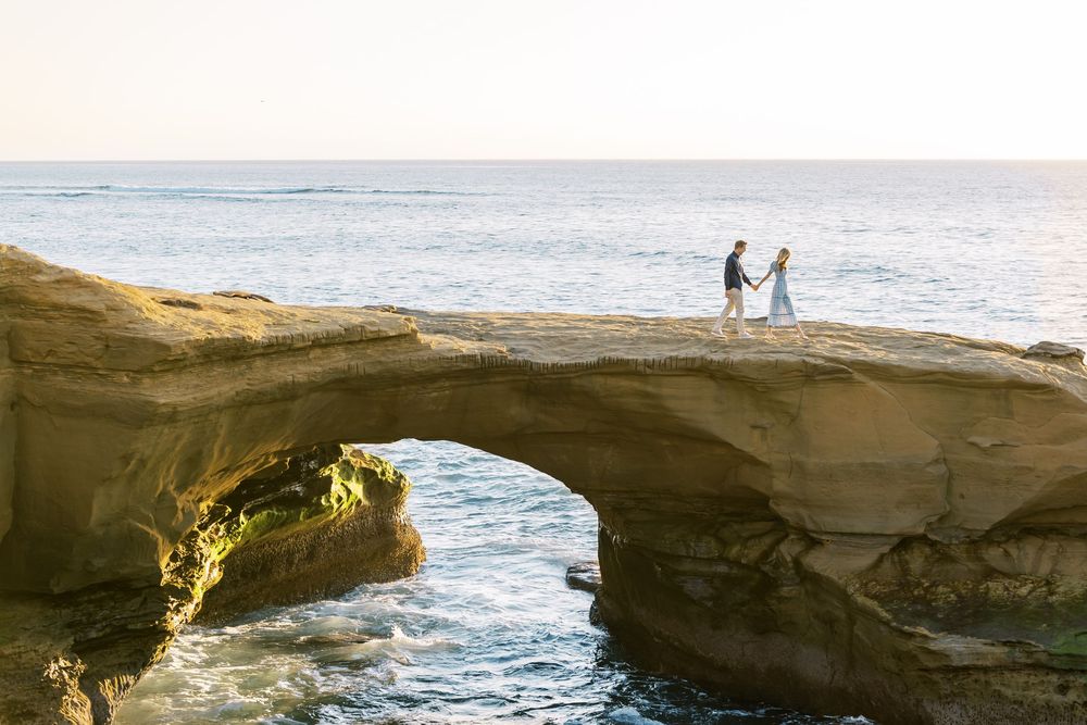 Rocky coastal cliffs and ocean waves create a dramatic landscape at sunset.
