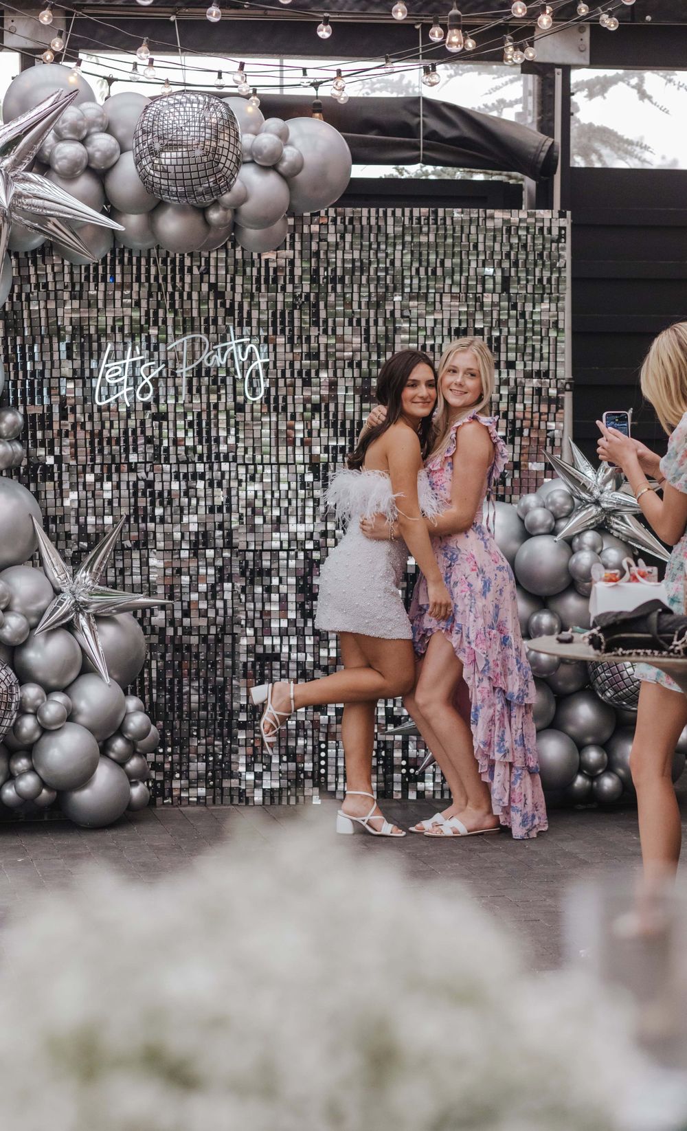 Silver disco ball and balloon arch creates a glamorous backdrop for a festive party scene.