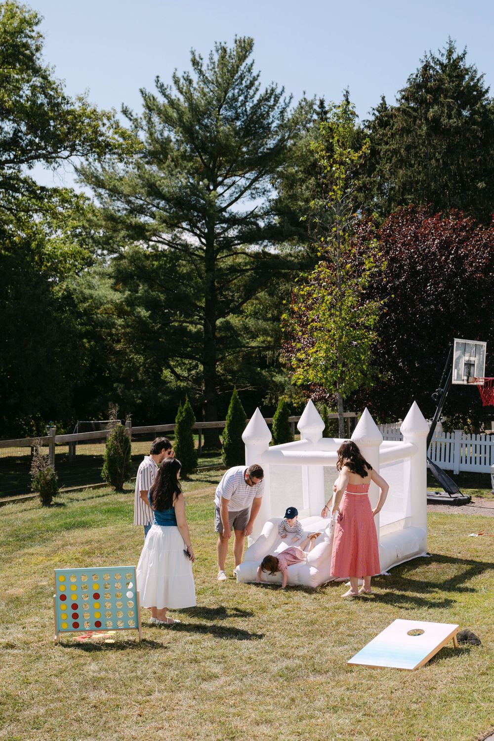 People enjoying outdoor games and activities at a backyard party with white decorative elements and lawn games.