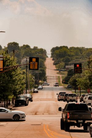 City street with traffic signals and parked cars leading up a steep hill.