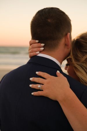 Detail photo of ring on the back of her husbands neck with the Florida sunset in the background on the beach