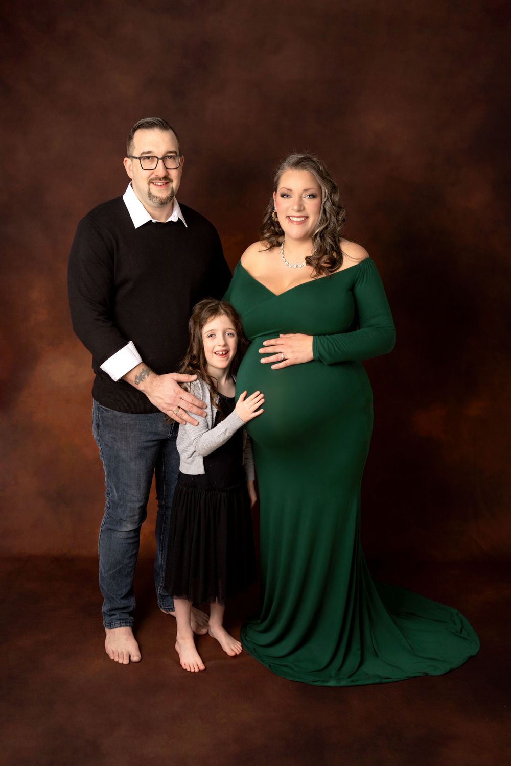 A family maternity portrait against a brown backdrop. Photography Halifax