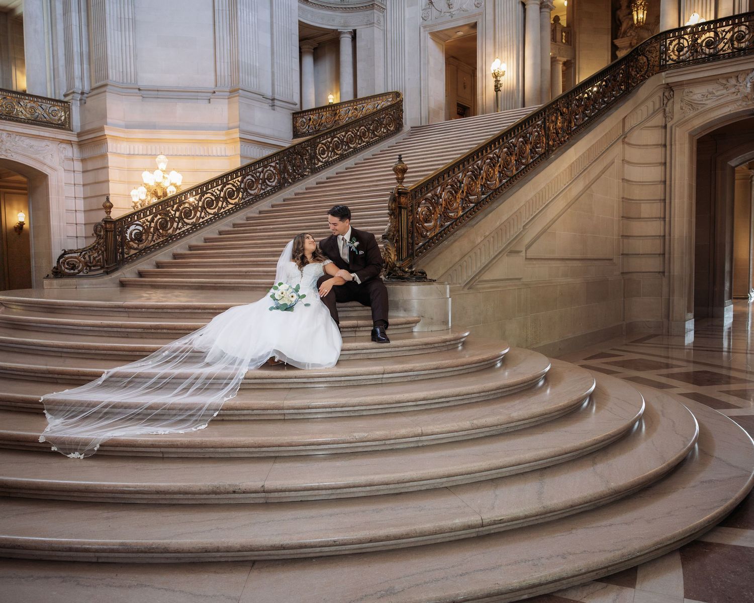 Bride and groom share a romantic moment on grand marble staircase at San Francisco City Hall wedding.