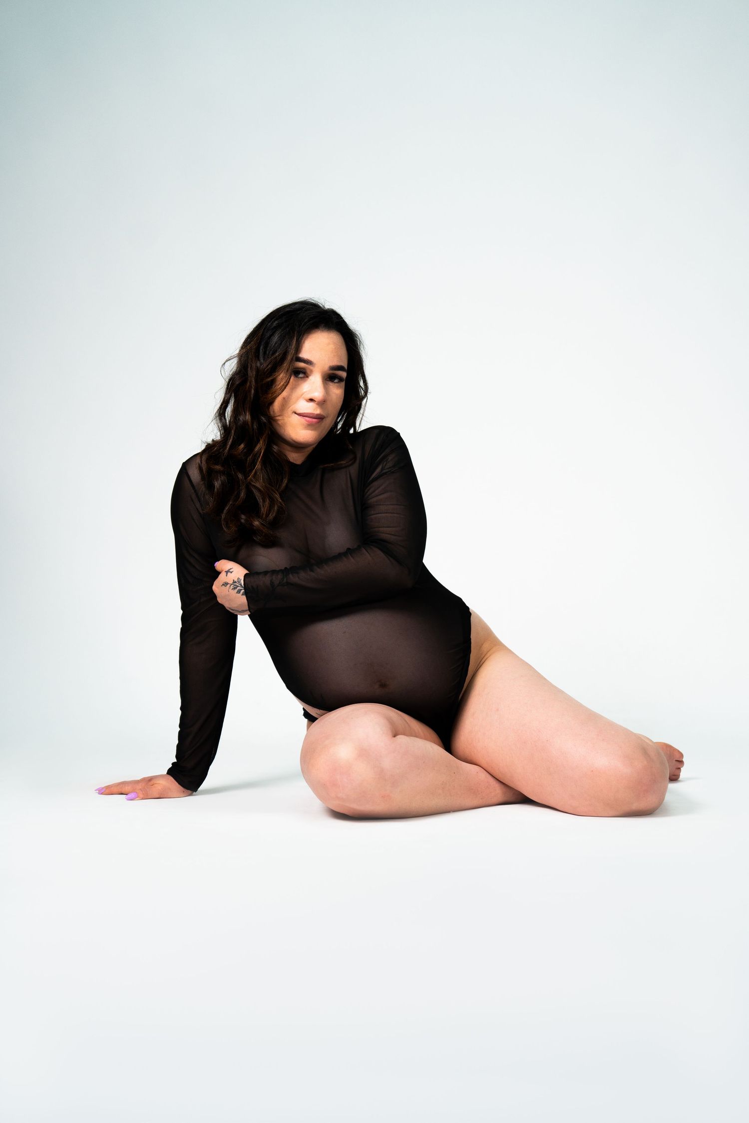 Artistic boudoir photography featuring black sheer clothing against white backdrop.