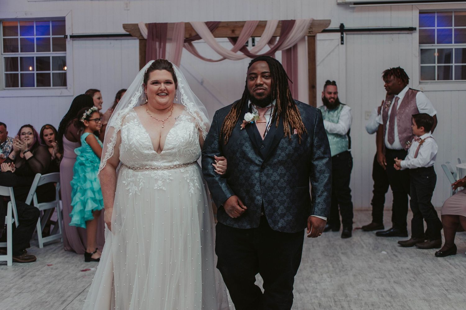 A joyful newlywed couple celebrates during their indoor wedding reception with guests.