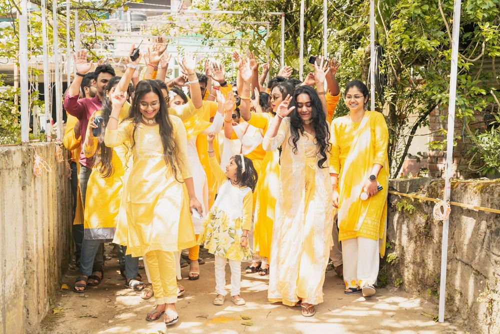 Celebratory gathering of people wearing coordinated yellow and white traditional outfits walking outdoors.
