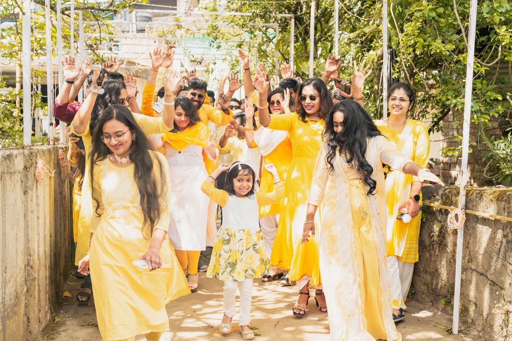 Festive crowd in bright yellow outfits dancing and celebrating on a sunny path.