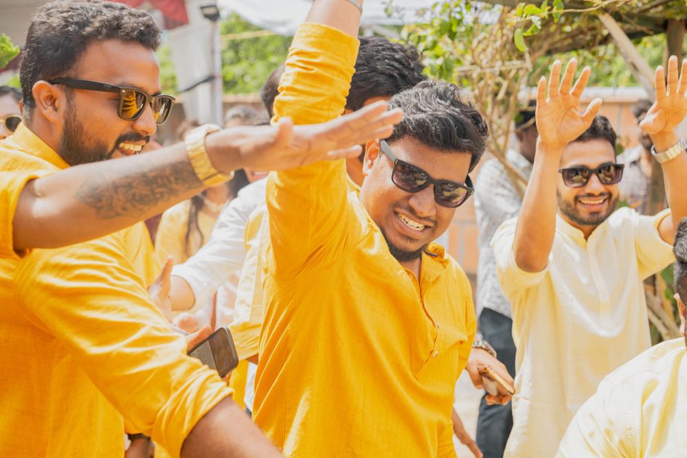 Three people in yellow attire dancing and celebrating with raised arms outdoors.