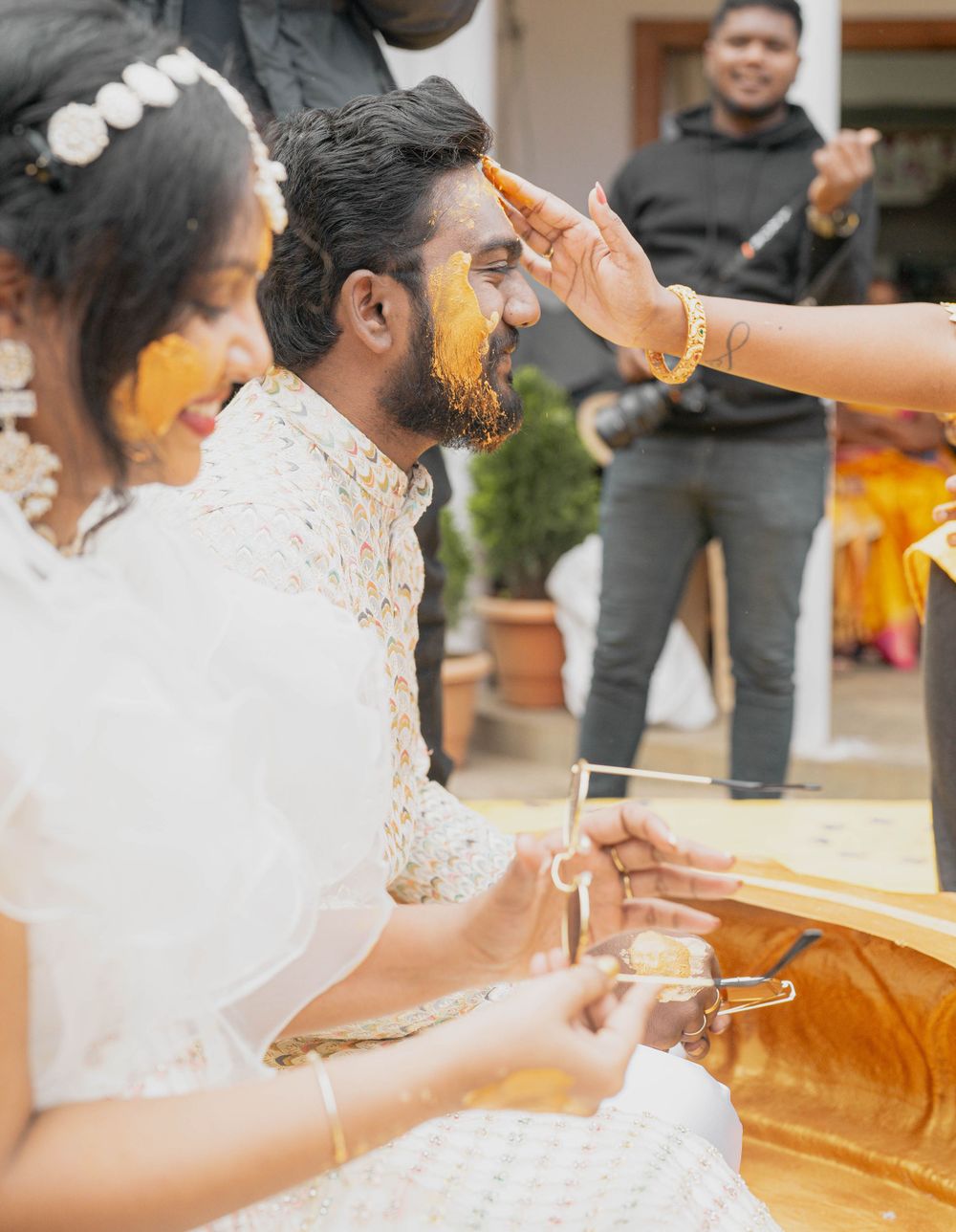 Traditional haldi ceremony in progress with yellow turmeric being applied during wedding rituals.
