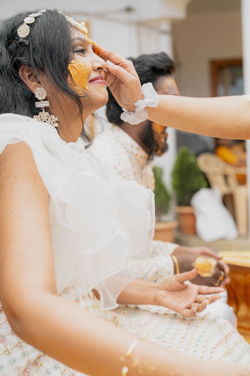 Yellow turmeric paste being applied during traditional Indian pre-wedding ceremony.