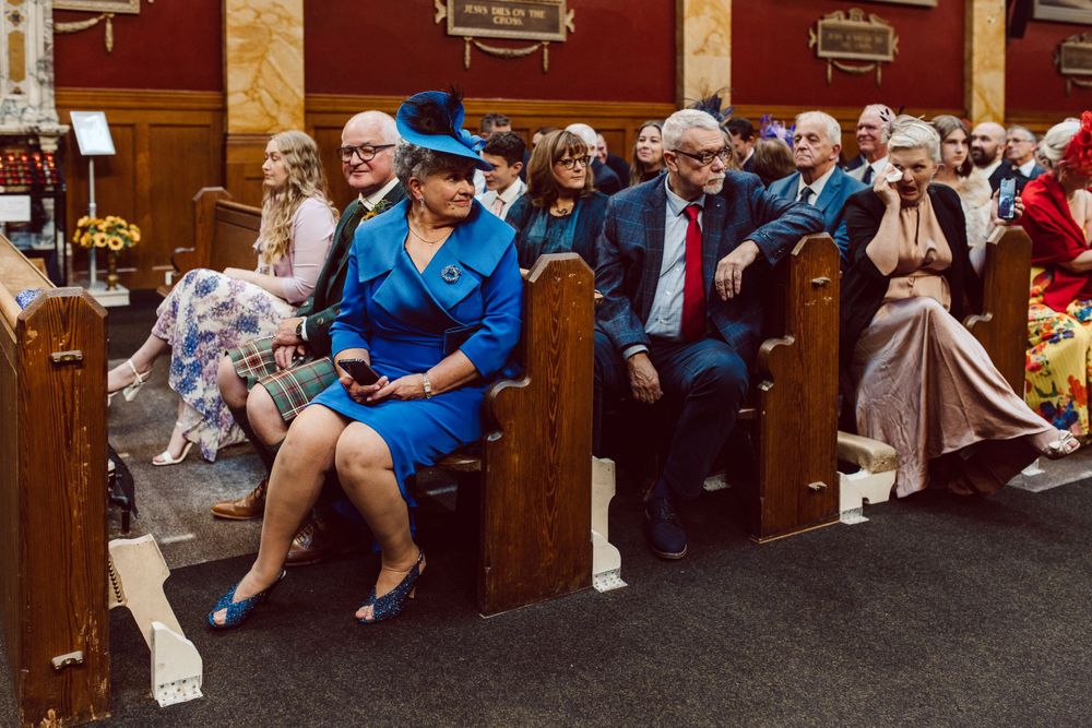 Wedding guests seated in wooden church pews during the ceremony.