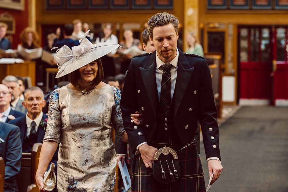 Wedding party members walking down the church aisle during a formal ceremony.