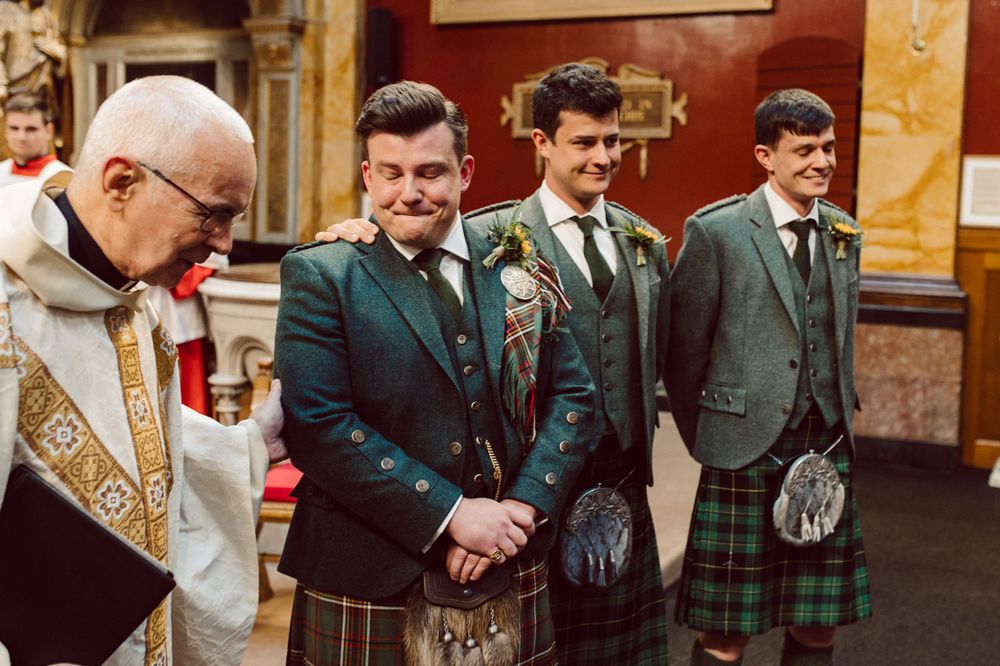 Wedding guests in kilts and formal attire gathered inside an elegant church sanctuary.