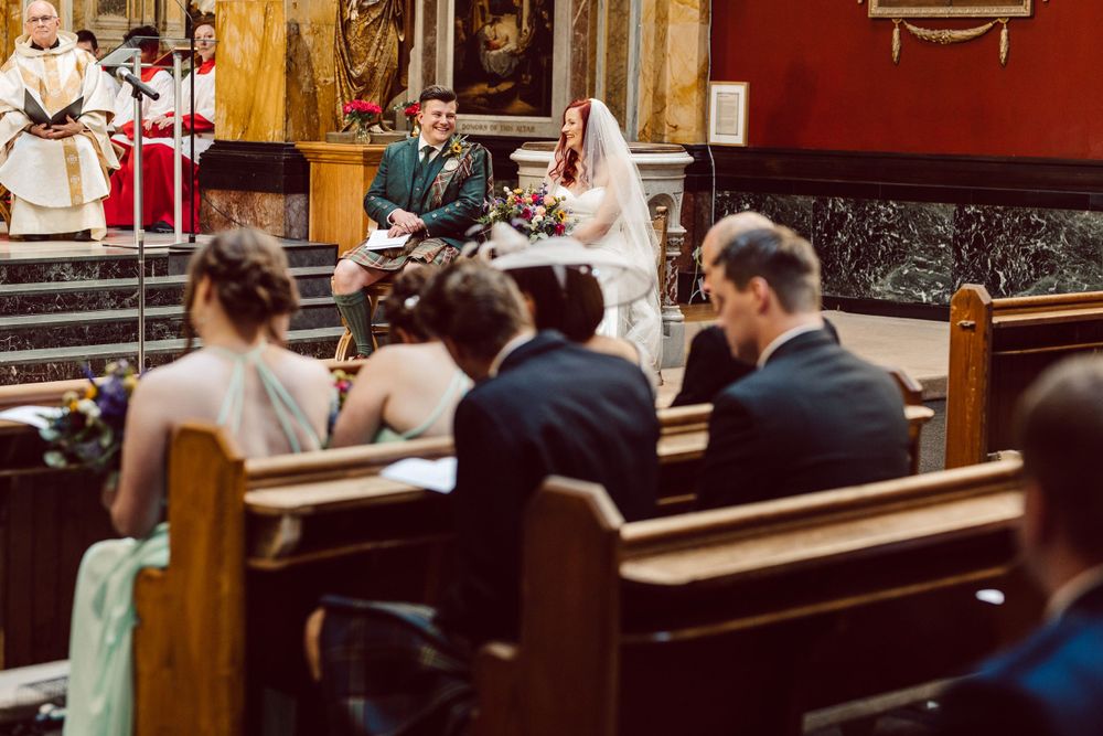 Side view of church sanctuary during wedding ceremony with guests seated in pews.