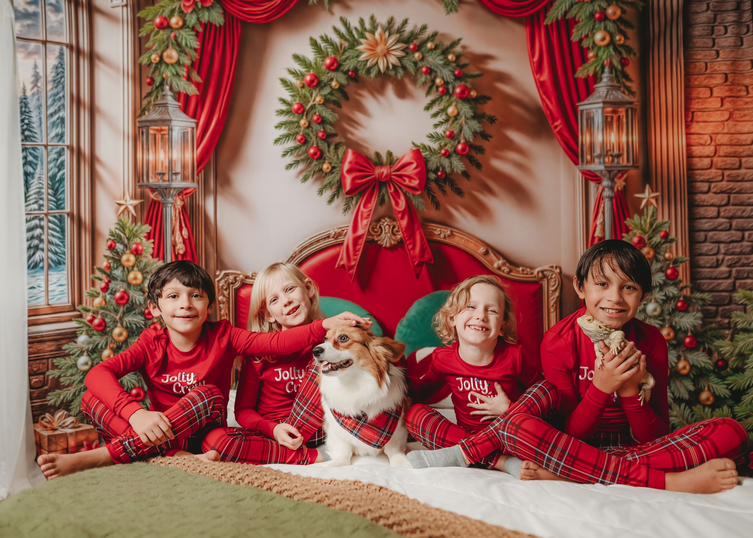 Holiday photo setup with red curtains, wreaths, and festive Christmas decorations against a brick wall.