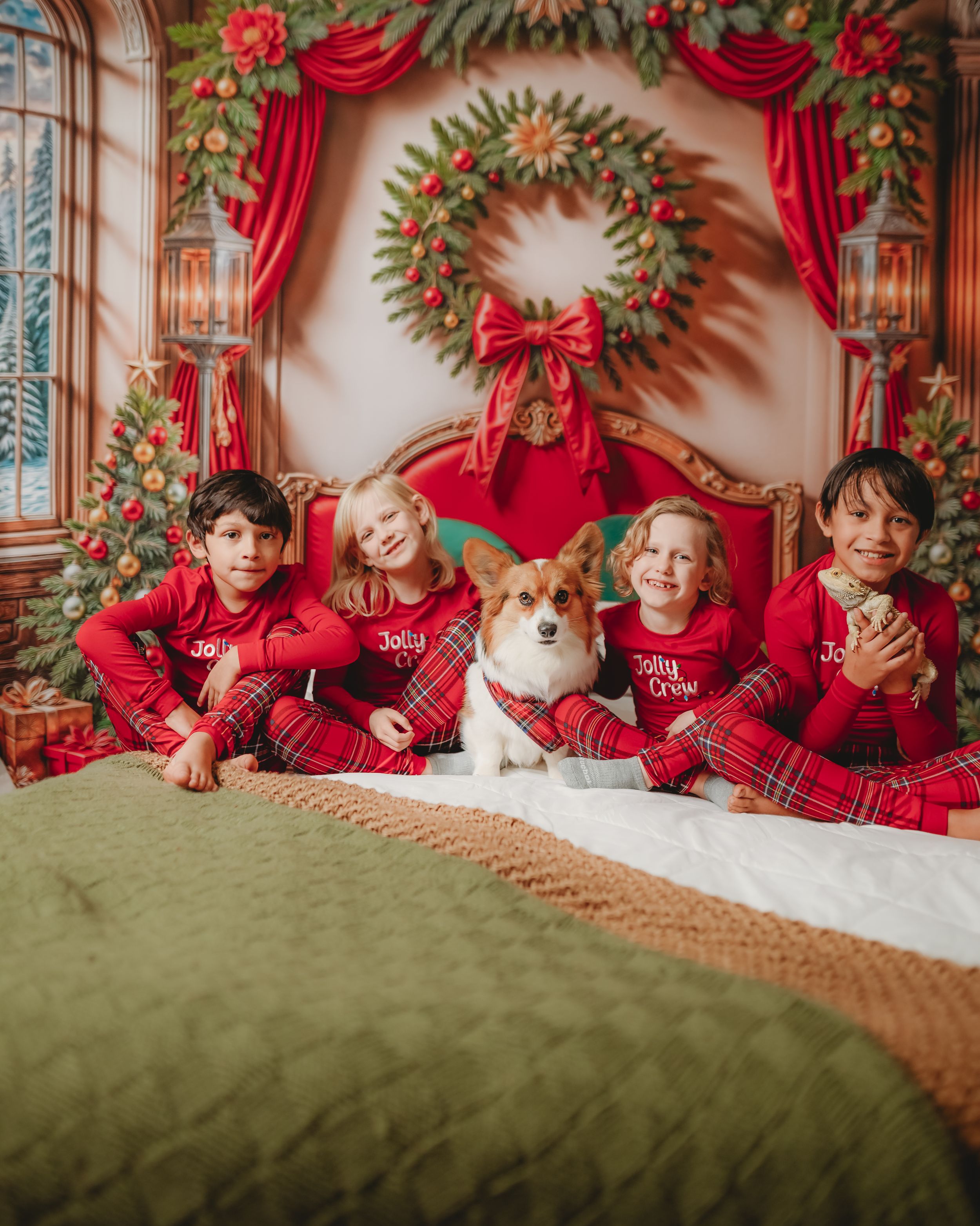 Christmas photo setting with red curtains, wreaths and decorative holiday elements on display.