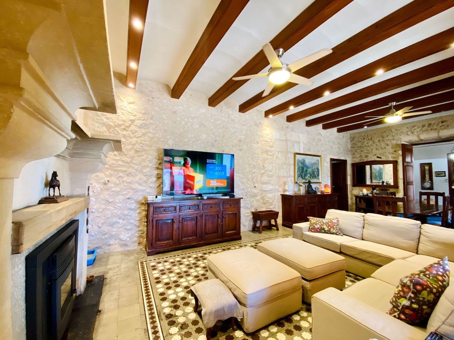 Luxurious living room with exposed ceiling beams, stone walls, and plush sectional sofa.