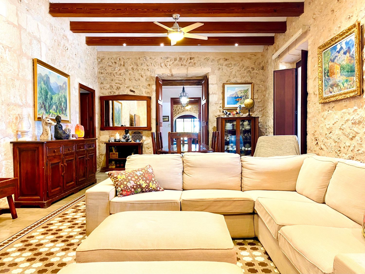Elegant living space featuring stone walls, wooden beams, and cream-colored sectional sofa.