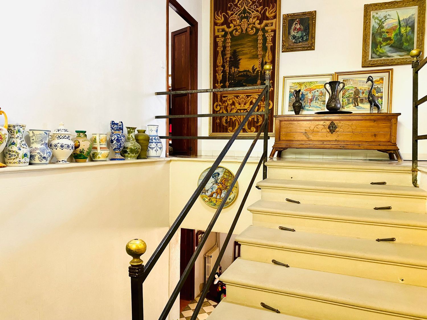 Staircase with black metal railings and decorative artwork featuring vintage tapestries.