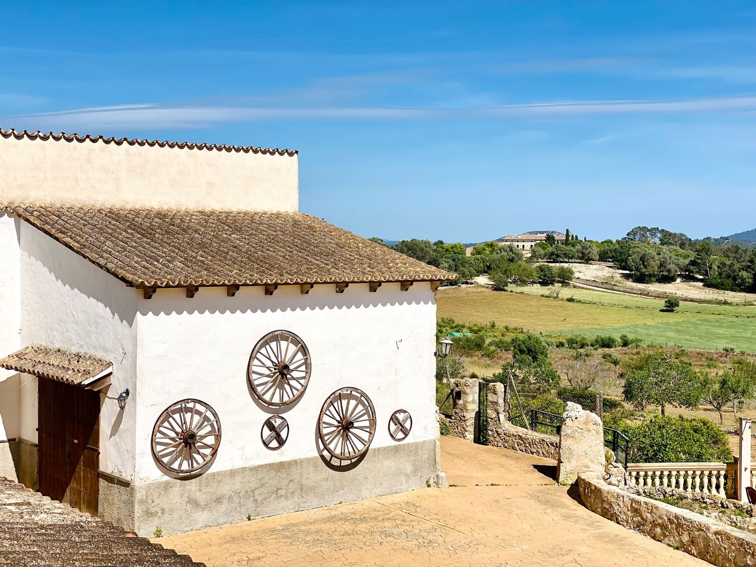White building exterior with decorative wheel motifs and rustic tiled roof against blue sky.