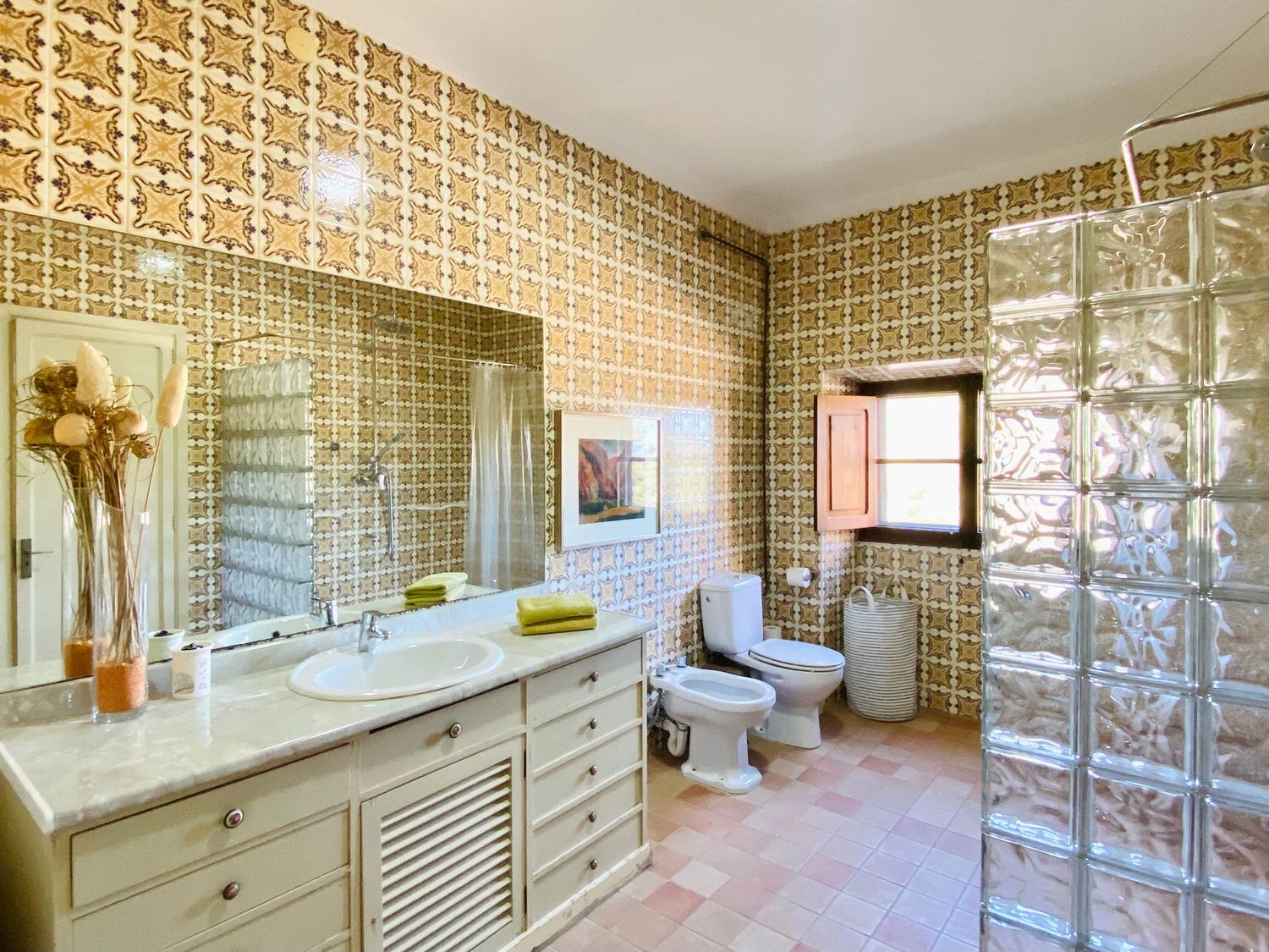 Retro bathroom with geometric wallpaper, glass block wall, and vintage-style vanity.