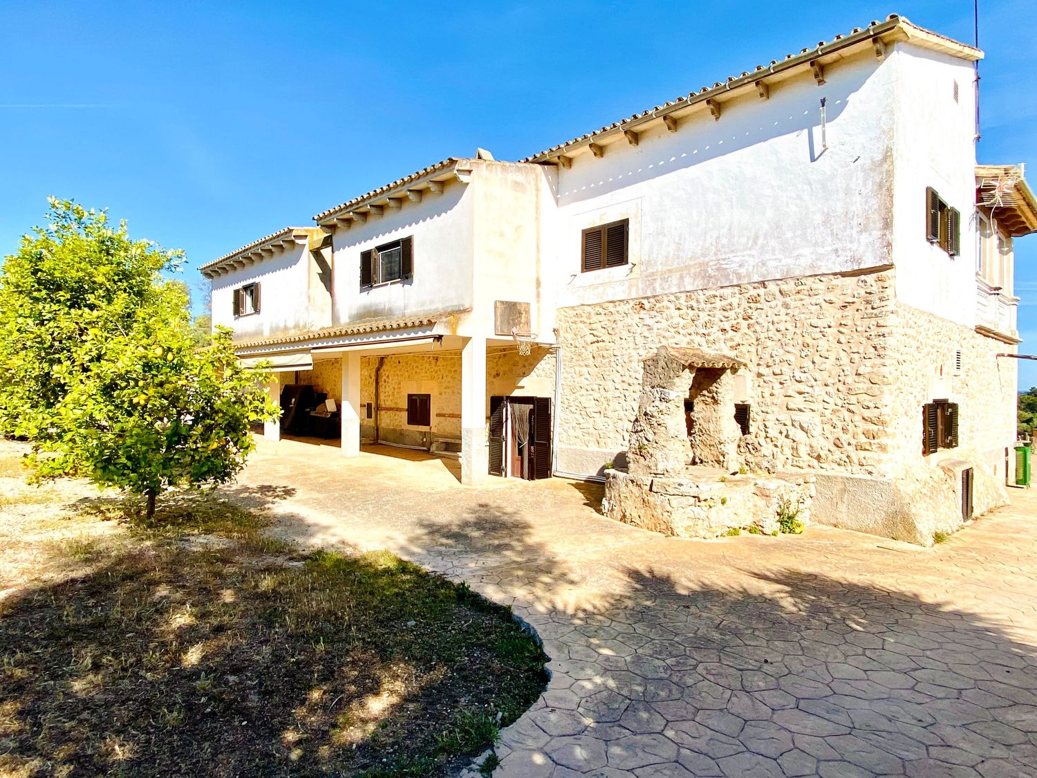 Traditional white Mediterranean villa with stone foundation and terracotta roof tiles.