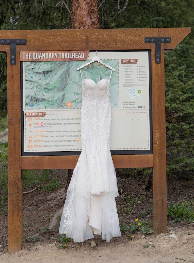 mermaid style wedding dress hanging on a post