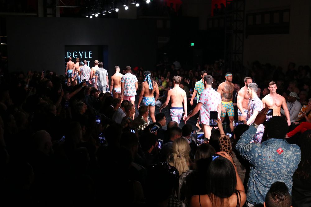 Group of models in summer outfits lined up on fashion show runway.