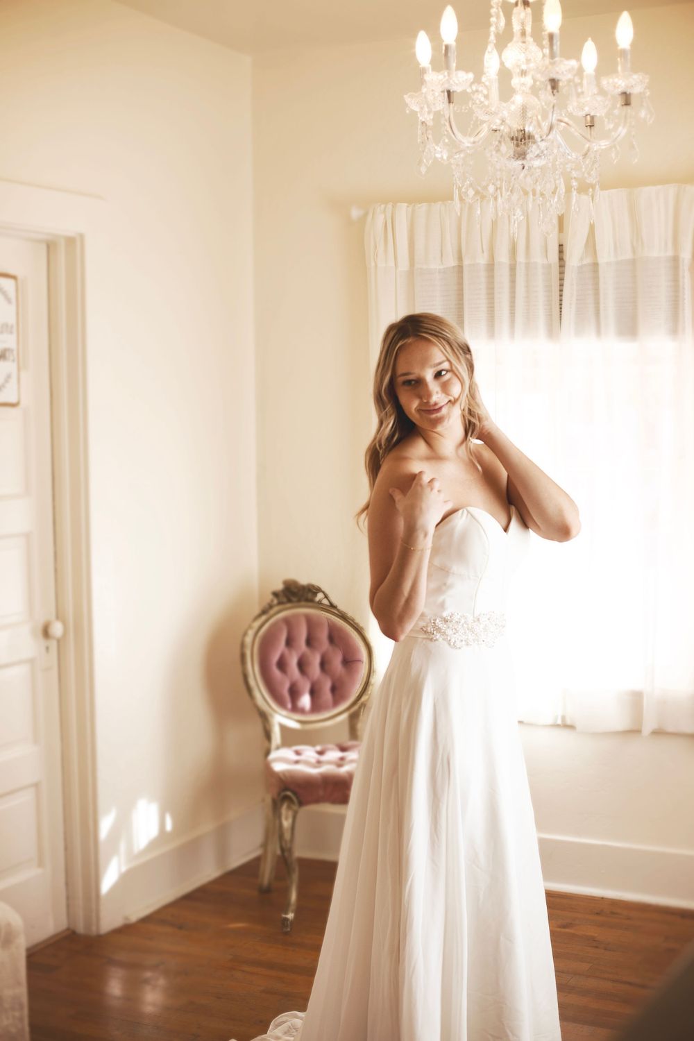 Elegant bridal portraits in bright indoor setting with crystal chandelier and vintage furniture.