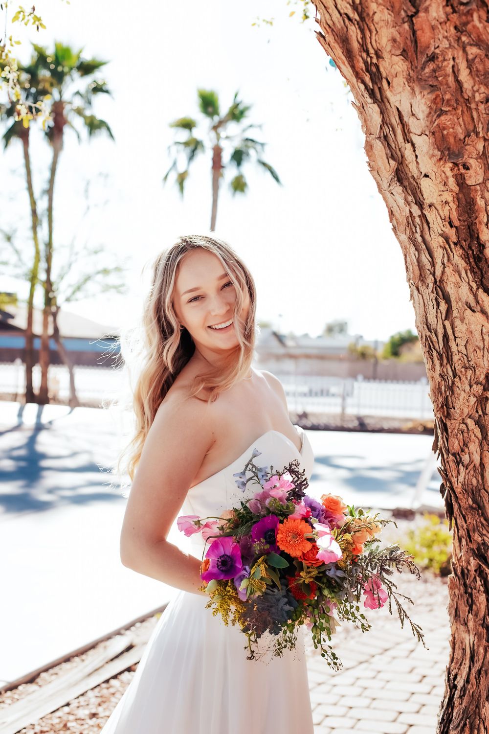 Sun-filled bridal portraits with colorful bouquet against desert palm tree backdrop.