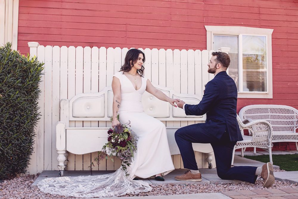 Wedding couple posing playfully in front of a red barn with white trim.