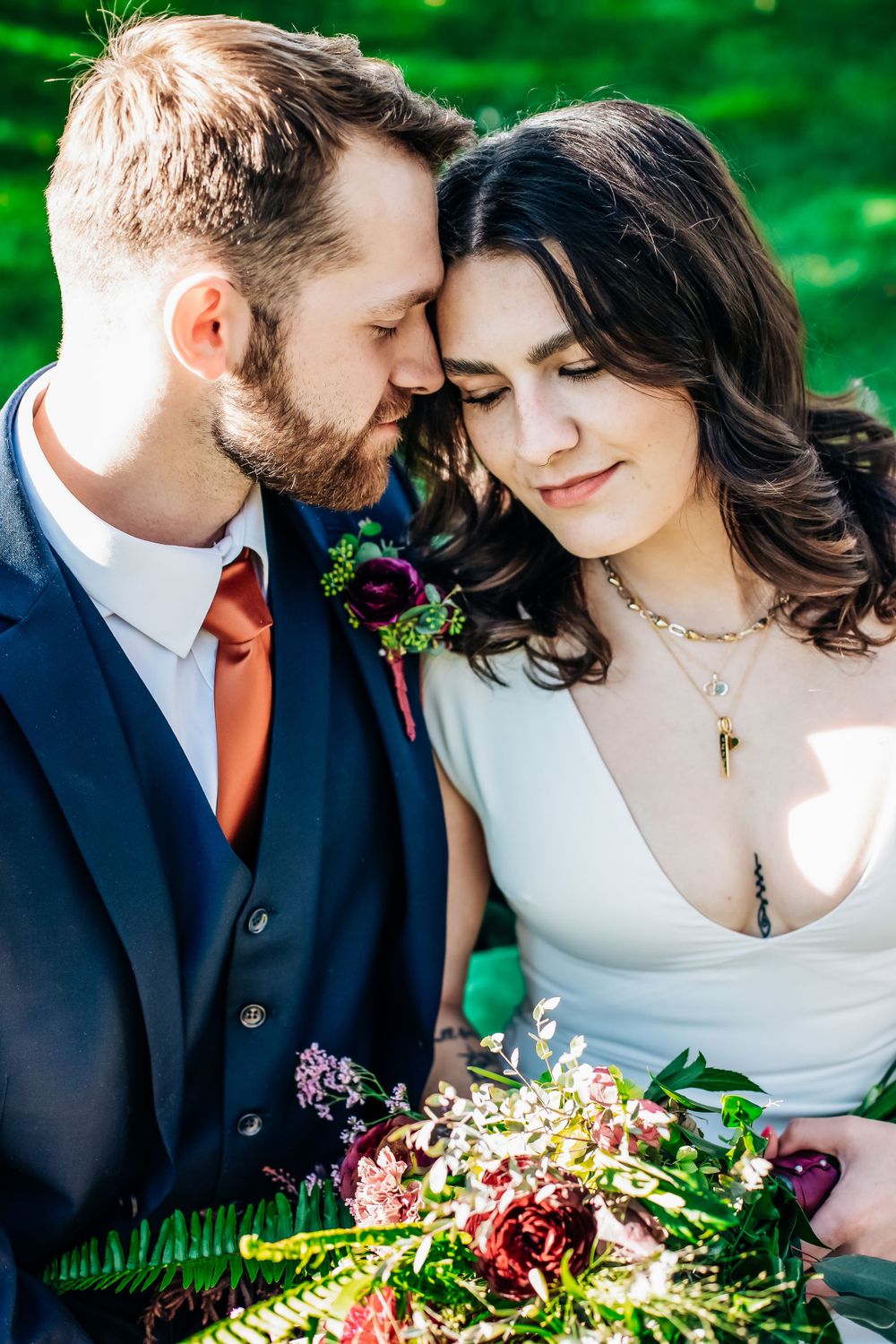 Romantic wedding couple sharing intimate moments with colorful floral bouquet in lush garden setting.