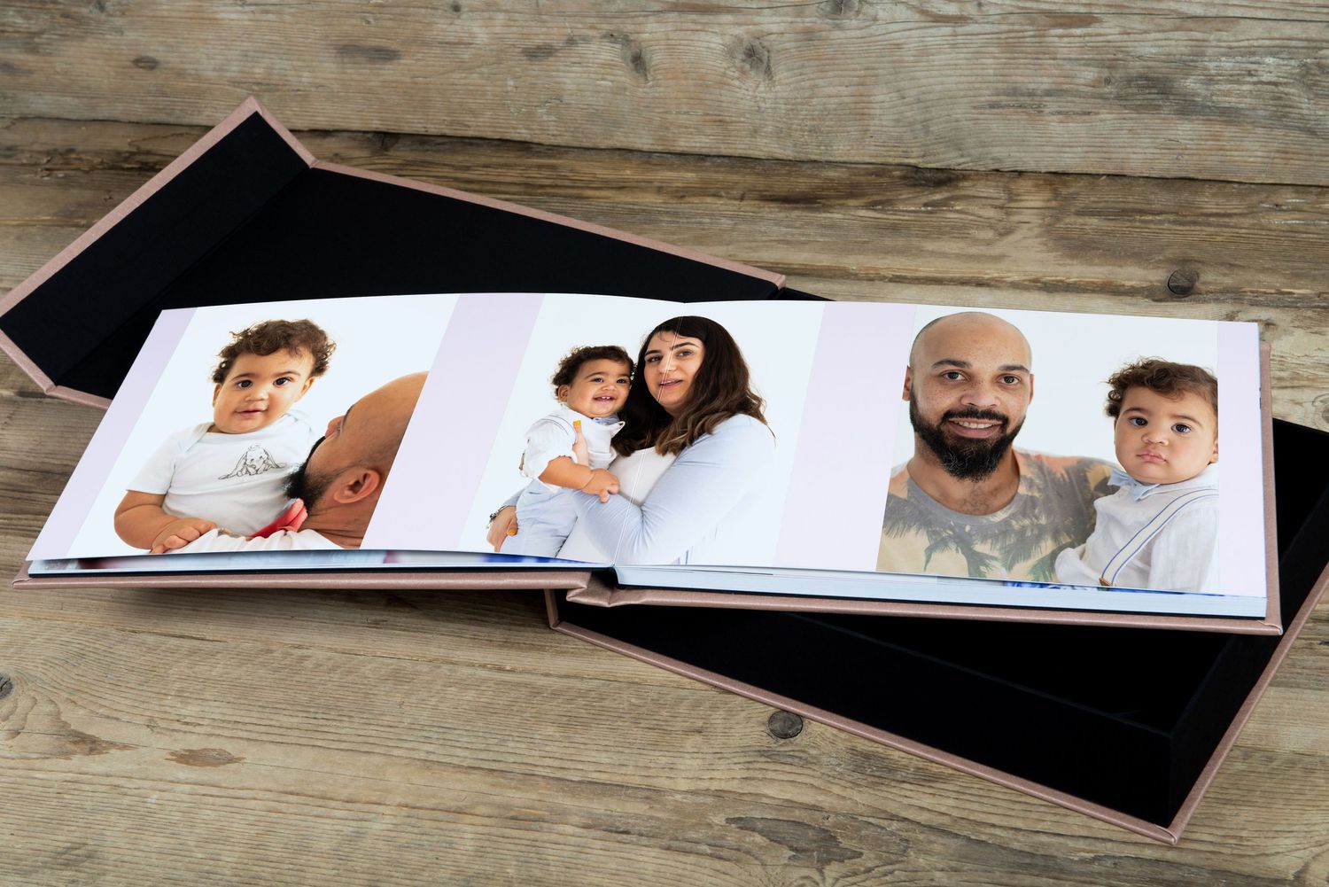 Professional photo album displaying family portraits on wooden surface.