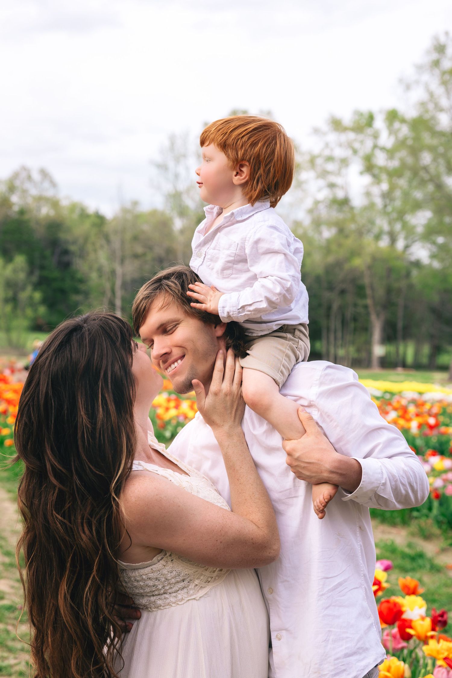 A parent and child play together in a vibrant tulip garden on a sunny spring day.