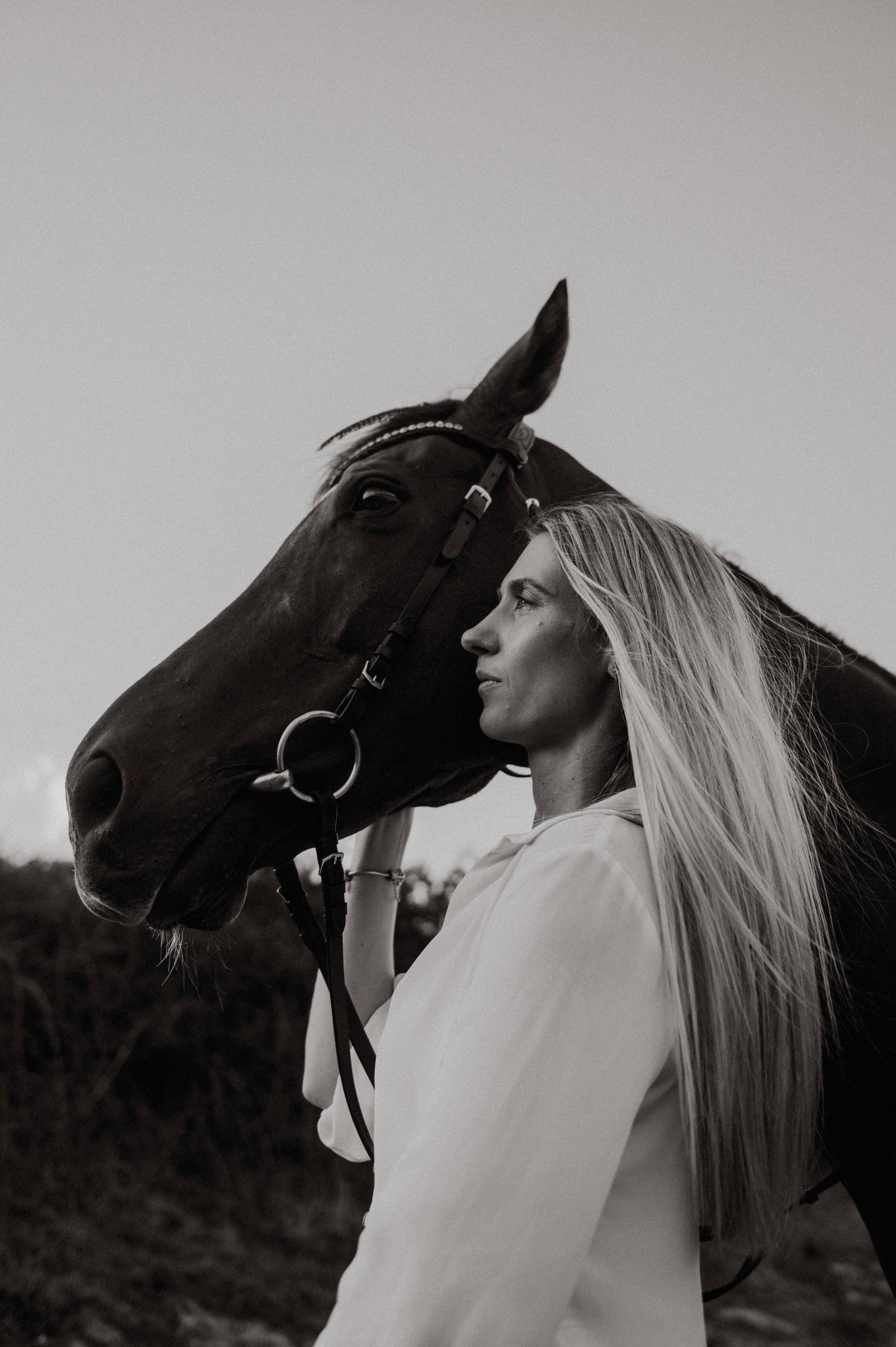 Portrait of a woman standing with her horse, capturing a calm and emotional bond between human and animal in a natural outdoor setting