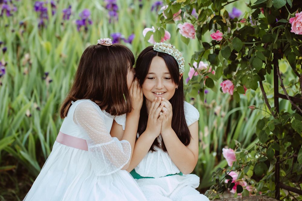 Two people sharing secrets in a garden surrounded by purple irises and pink flowers.