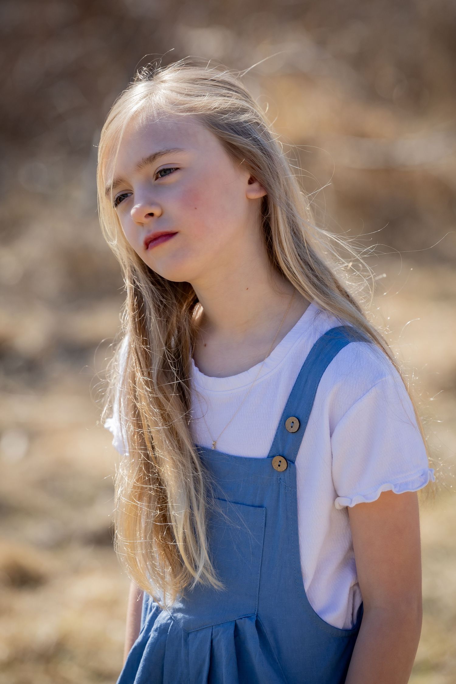 Portrait series of young person in blue dress against natural backdrop.