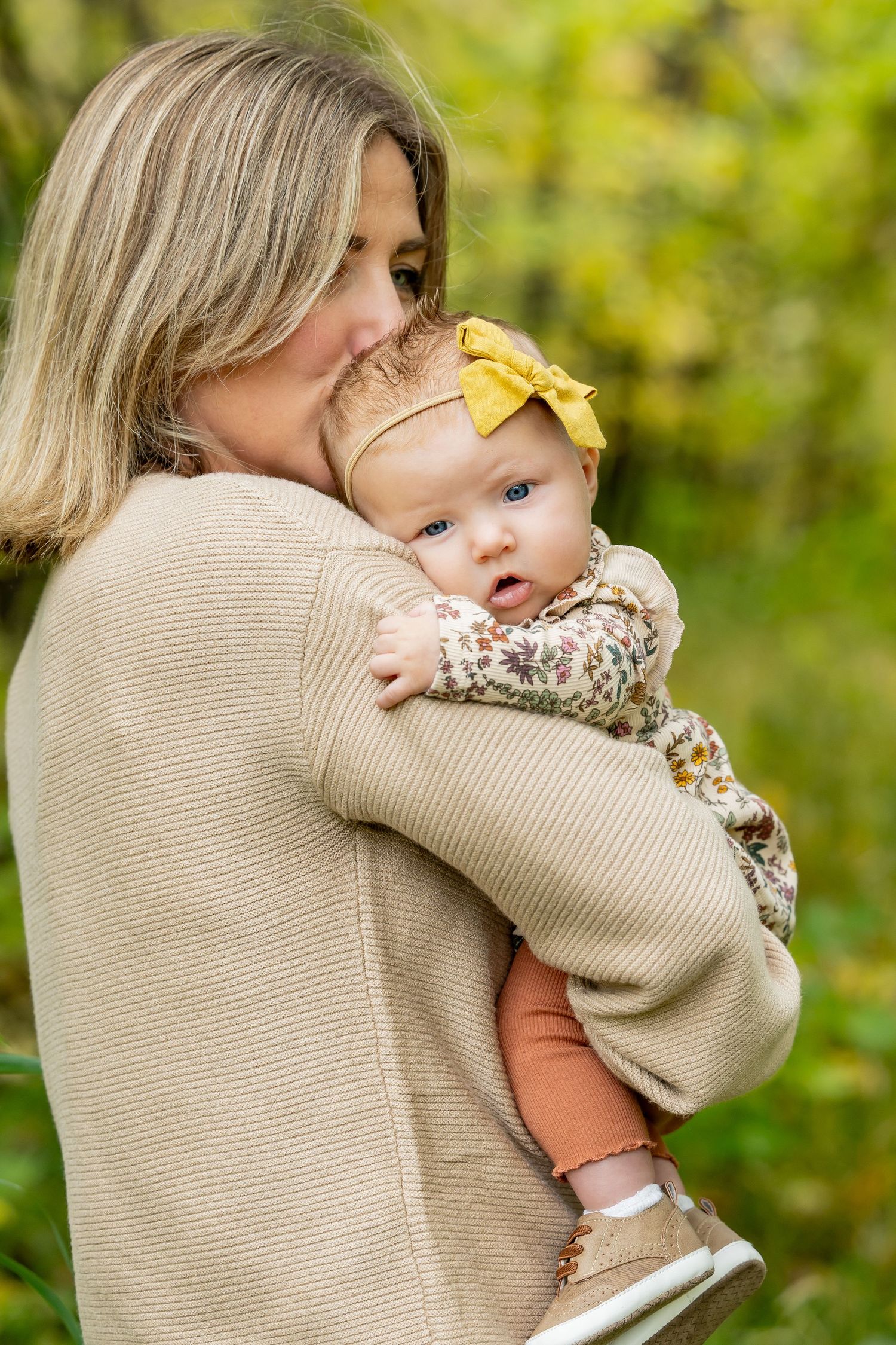 Tender moments captured between parent and baby in outdoor autumn setting.