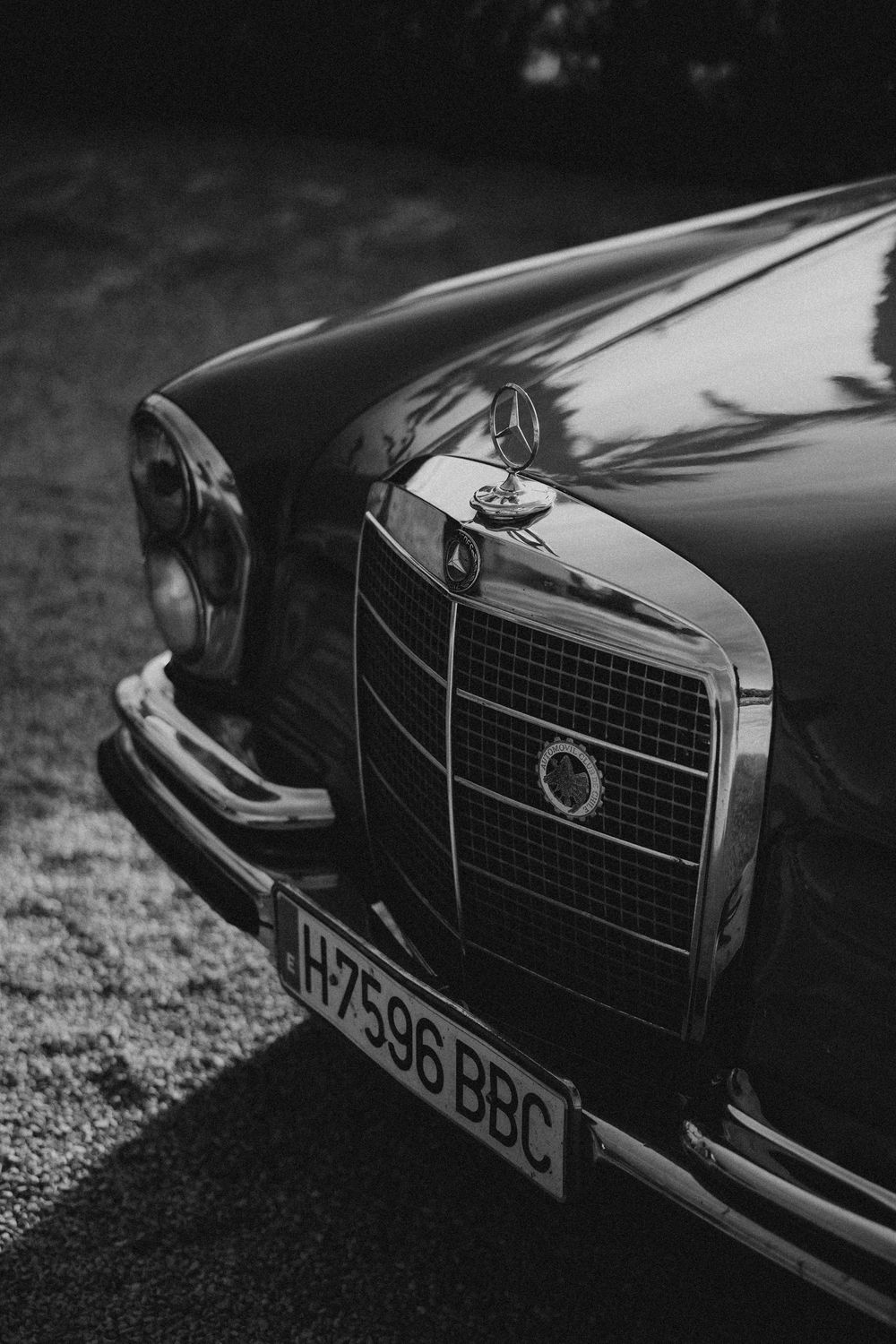 A series of black and white close-up shots showing the front grille and hood ornament details of a classic luxury car.