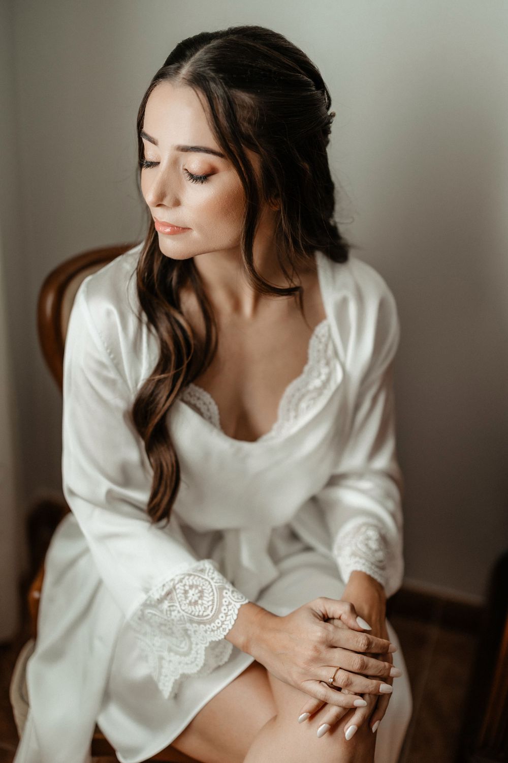 Woman in white sweater poses elegantly in moody boudoir photoshoot with soft lighting and romantic aesthetic.