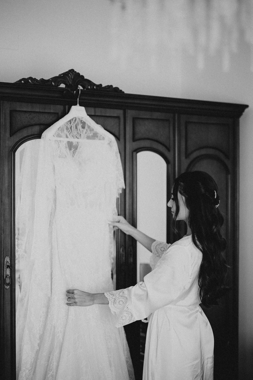 A sequence of black and white photos showing a person in a white dress or robe standing against dark wooden cabinets.