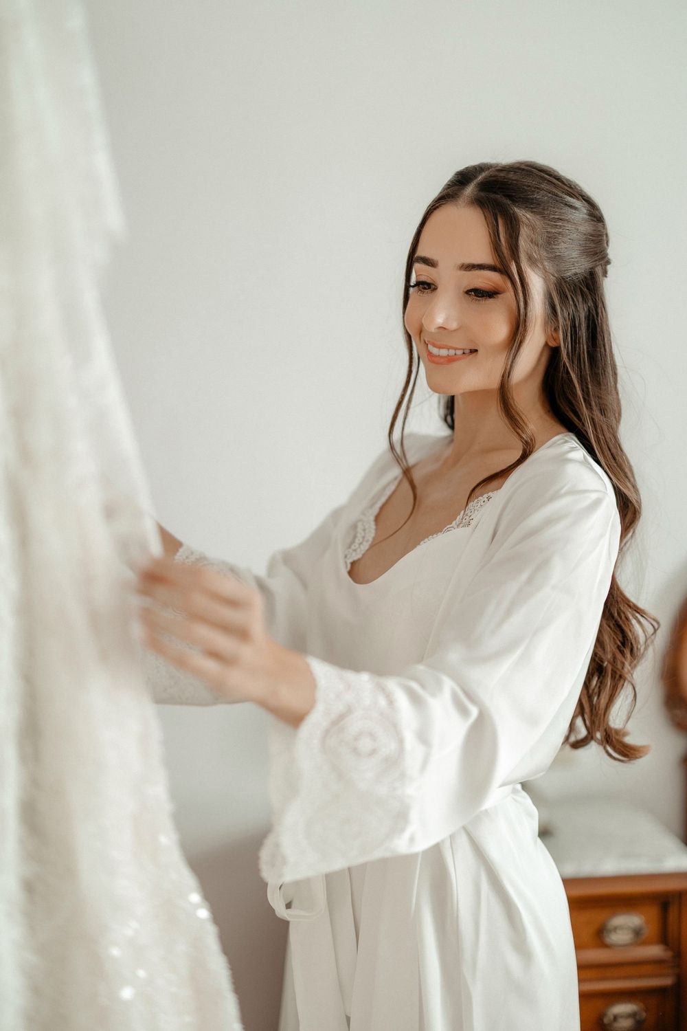 Person in white robe smiling and dancing gracefully in a bright, airy room with natural light.