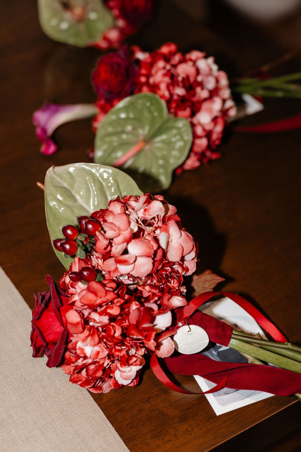 Red and pink heart-shaped confetti scattered on paper with green leaves creates a romantic Valentine's Day composition.