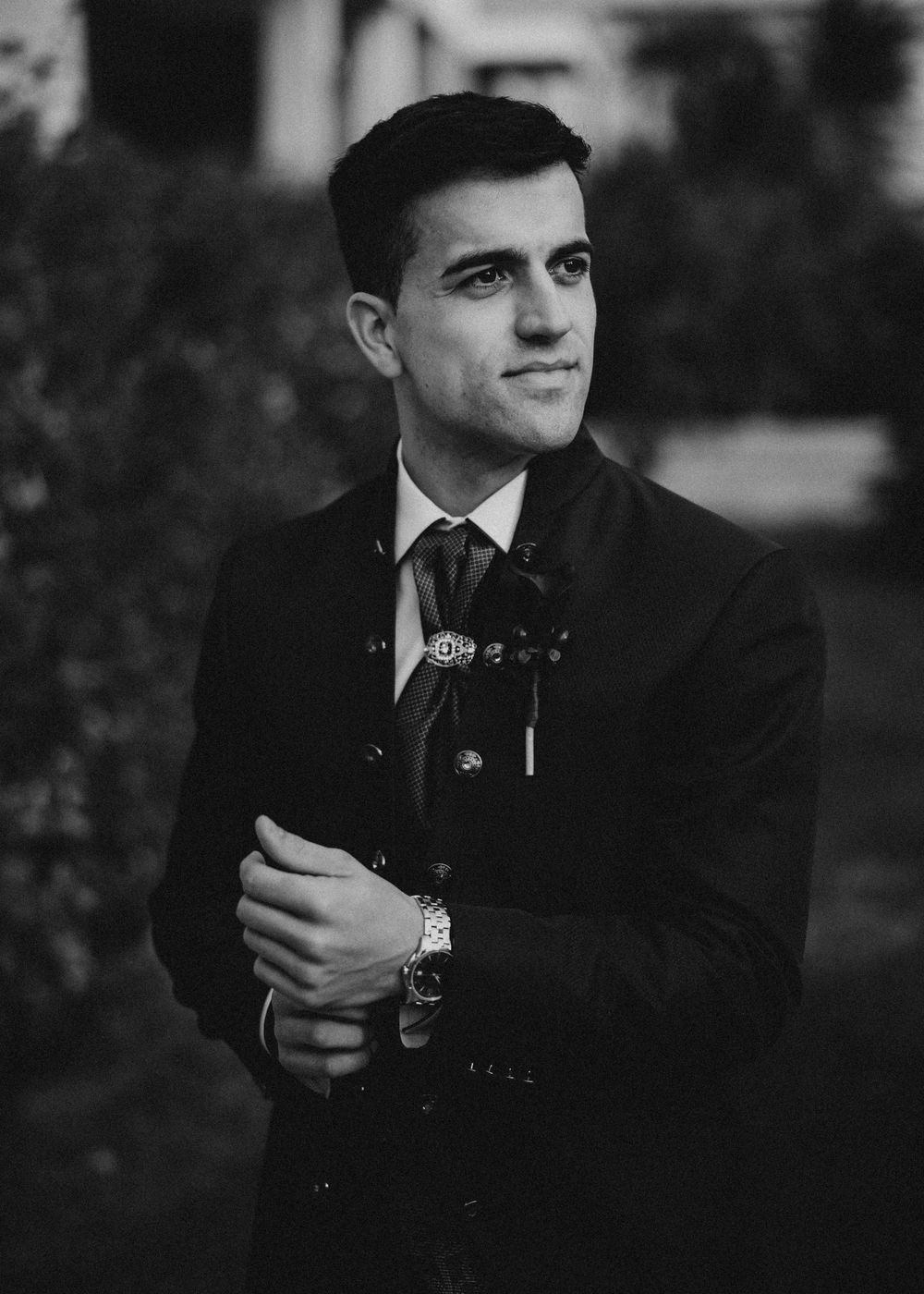 A black and white portrait series showing a man in a suit adjusting his watch and looking away from the camera.